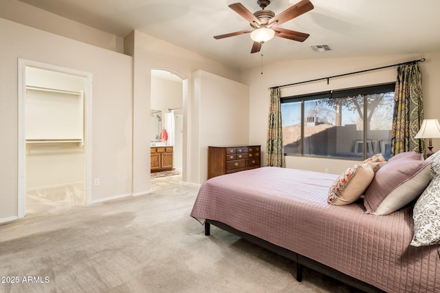 carpeted bedroom featuring ensuite bathroom, ceiling fan, vaulted ceiling, and a walk in closet