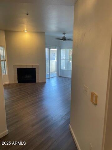 unfurnished living room featuring dark wood-type flooring and ceiling fan