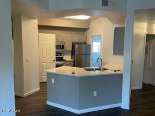 kitchen with dark wood-type flooring, stainless steel appliances, kitchen peninsula, and sink