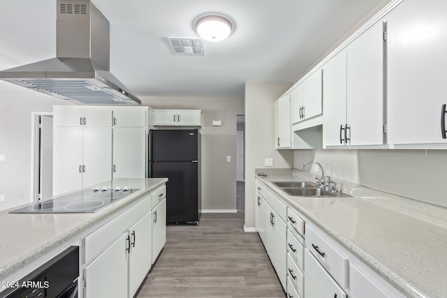 kitchen with sink, white cabinets, wall chimney range hood, light hardwood / wood-style flooring, and black appliances