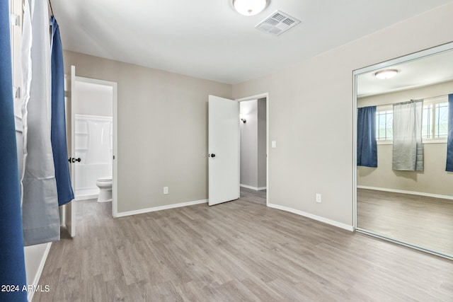 unfurnished bedroom featuring light wood-type flooring and ensuite bath