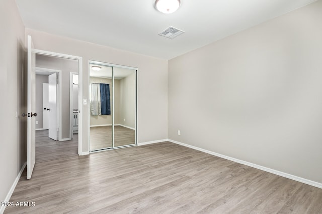 unfurnished bedroom featuring light hardwood / wood-style flooring and a closet