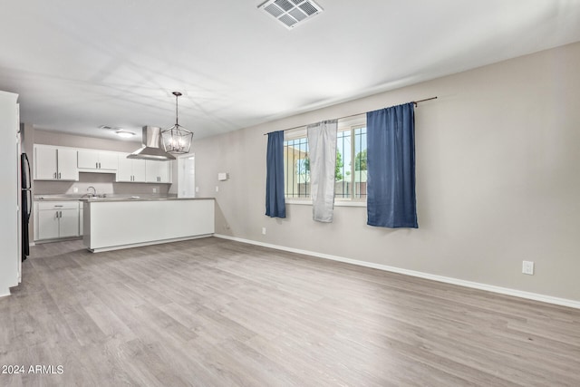 unfurnished living room featuring a notable chandelier and light hardwood / wood-style floors