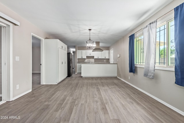 kitchen with white cabinets, decorative light fixtures, light hardwood / wood-style floors, and a wealth of natural light