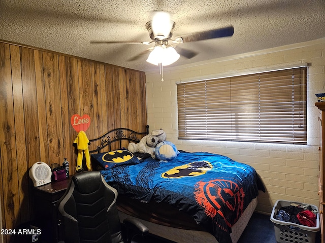 bedroom with ceiling fan, a textured ceiling, and wood walls