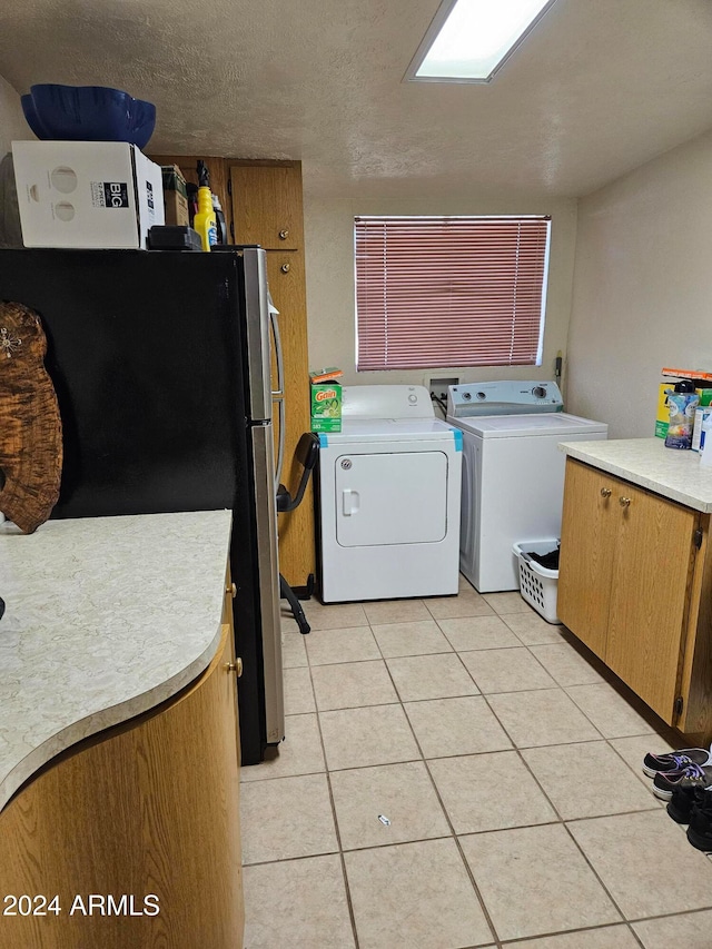 laundry room with washer and clothes dryer, a textured ceiling, and light tile patterned floors