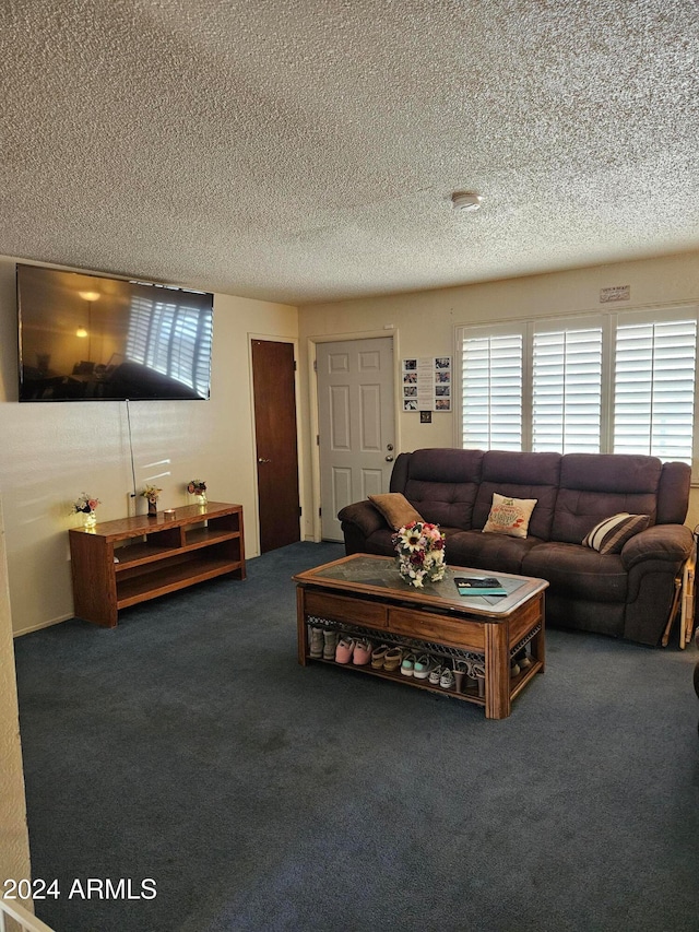 living room with a textured ceiling, a wealth of natural light, and dark colored carpet