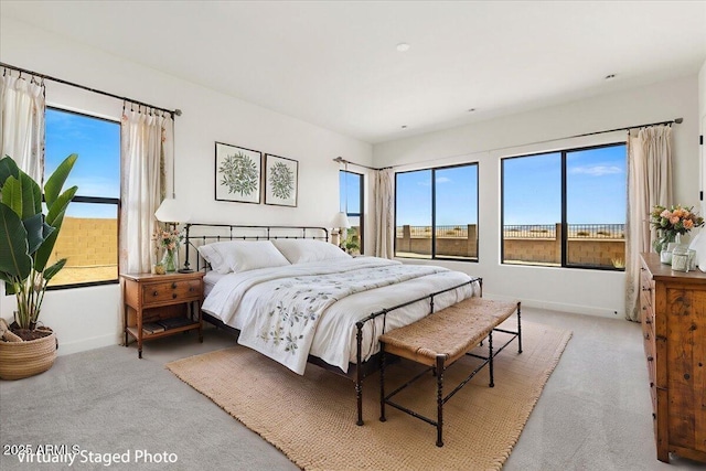 carpeted bedroom featuring multiple windows and baseboards