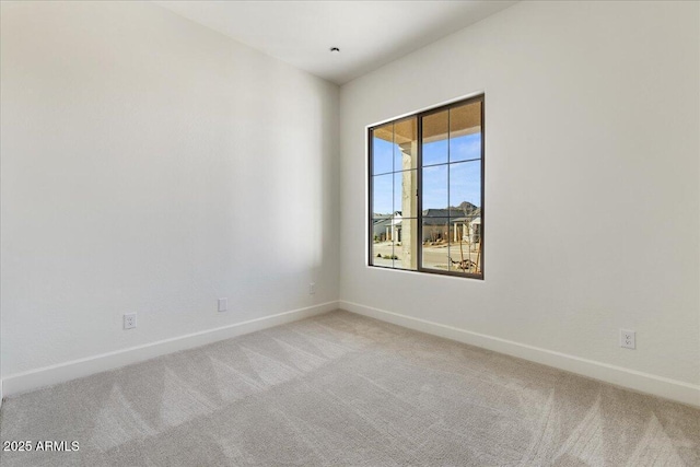 unfurnished room featuring light colored carpet and baseboards