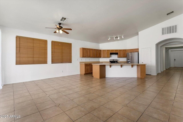 kitchen with a center island with sink, visible vents, a breakfast bar area, stainless steel appliances, and light countertops