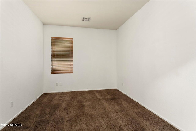 unfurnished room with baseboards, visible vents, and dark colored carpet