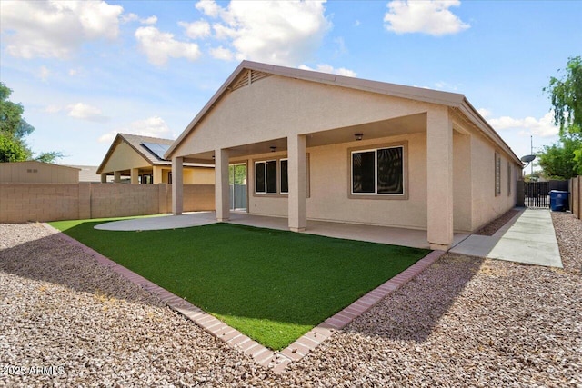 rear view of house featuring a lawn, a patio area, a fenced backyard, and stucco siding