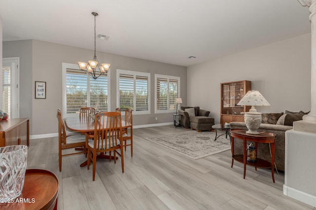 dining area with light hardwood / wood-style floors, plenty of natural light, and a chandelier