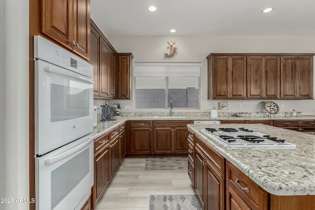 kitchen featuring light stone counters, sink, and white appliances