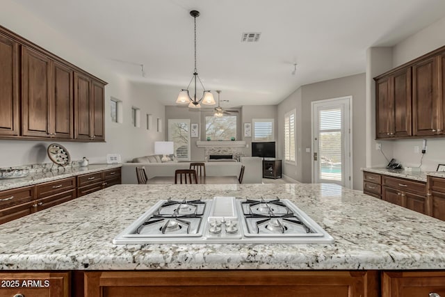 kitchen with stainless steel gas cooktop, light stone counters, and a center island