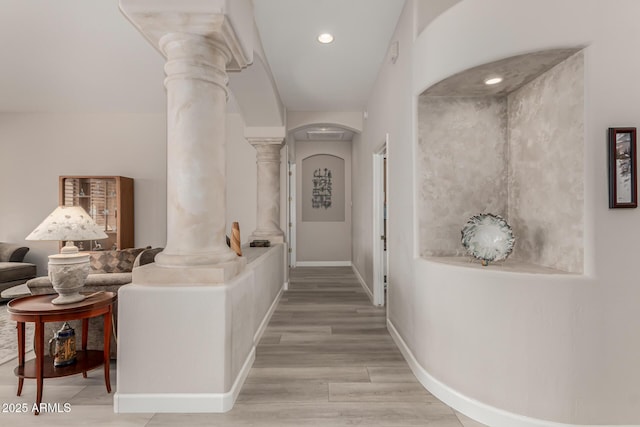 corridor featuring light hardwood / wood-style floors and decorative columns