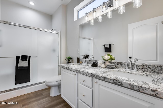 bathroom with hardwood / wood-style flooring, vanity, toilet, and a shower with door