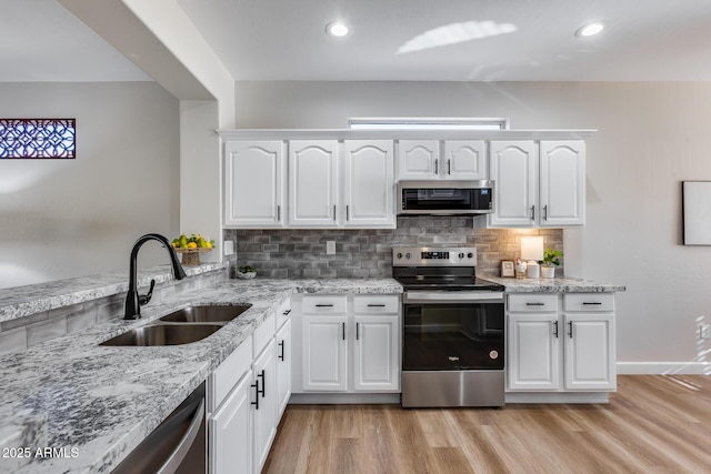 kitchen with appliances with stainless steel finishes, light hardwood / wood-style floors, white cabinetry, and sink