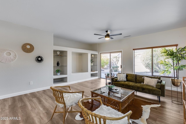 living room featuring built in shelves, ceiling fan, and hardwood / wood-style floors