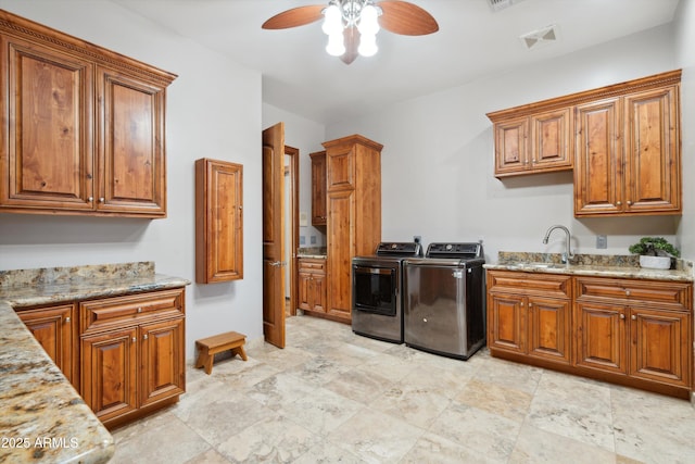 kitchen featuring sink, ceiling fan, light stone countertops, and washer and clothes dryer