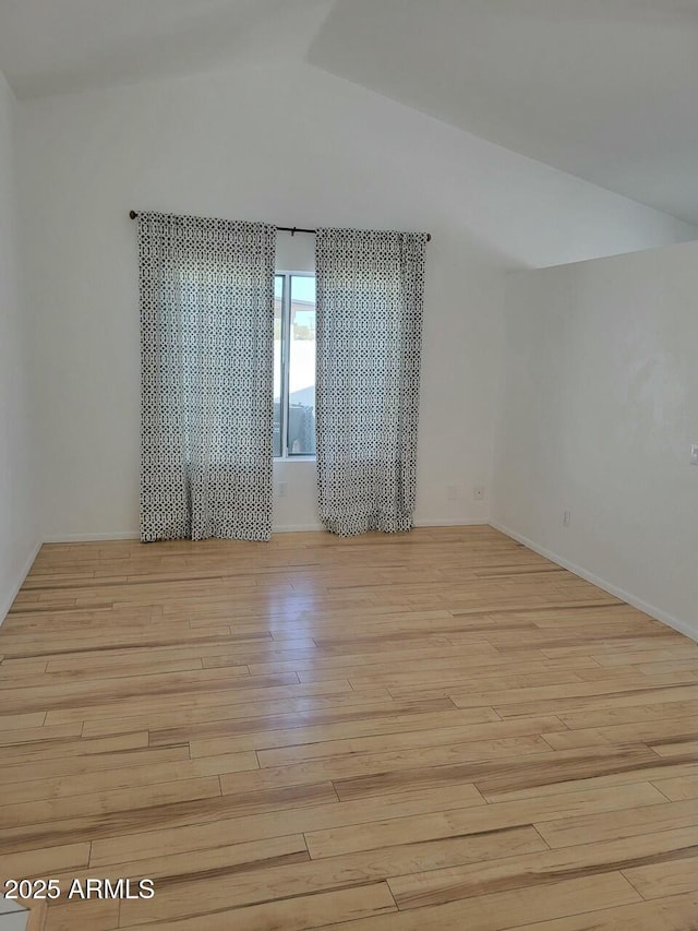 spare room with vaulted ceiling and light hardwood / wood-style flooring