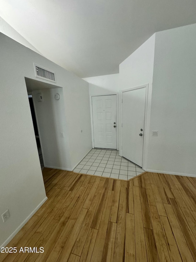 spare room with vaulted ceiling and light hardwood / wood-style floors