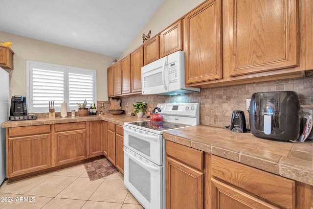 kitchen with white appliances, light tile patterned floors, backsplash, and lofted ceiling