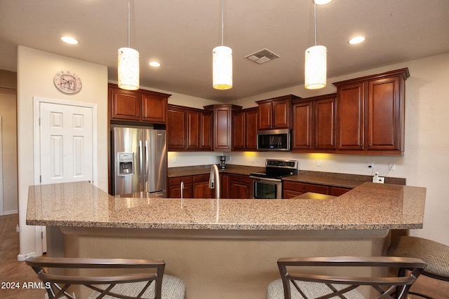 kitchen featuring a kitchen bar, hanging light fixtures, and appliances with stainless steel finishes