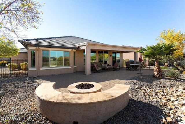 back of property with an outdoor living space with a fire pit and a patio area