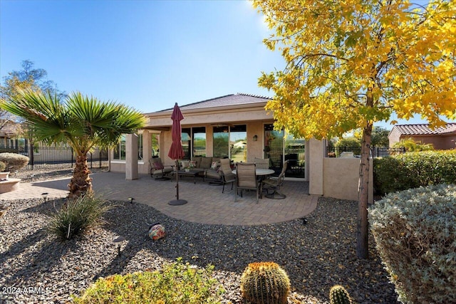 rear view of property with an outdoor living space and a patio