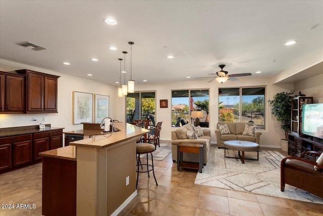 kitchen with a breakfast bar, dishwasher, a center island with sink, hanging light fixtures, and ceiling fan