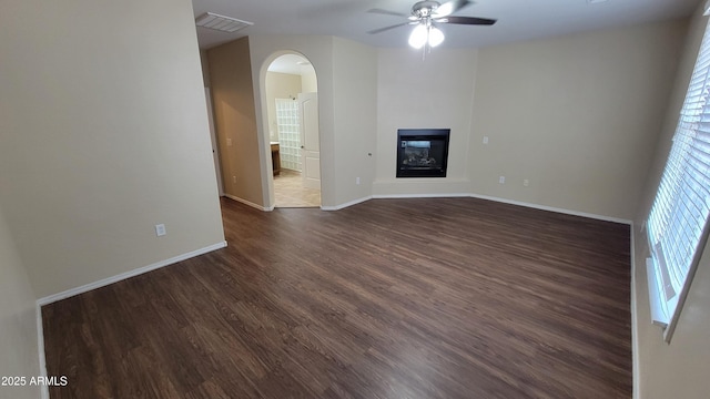 unfurnished living room featuring dark wood-type flooring and ceiling fan