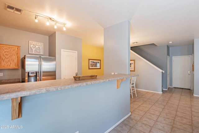 kitchen featuring a kitchen bar, stainless steel fridge with ice dispenser, and light brown cabinets