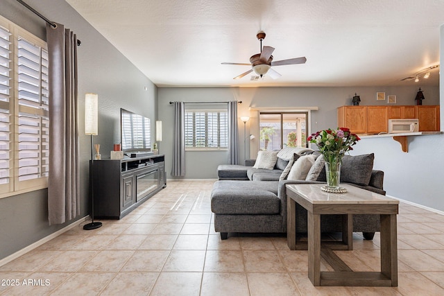 living room with ceiling fan, light tile patterned floors, track lighting, and a textured ceiling