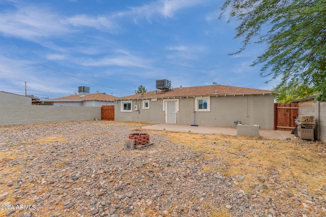 rear view of property with a fire pit, a patio, and central AC