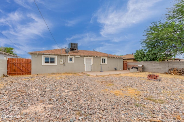 rear view of property featuring a fire pit, cooling unit, and a patio area