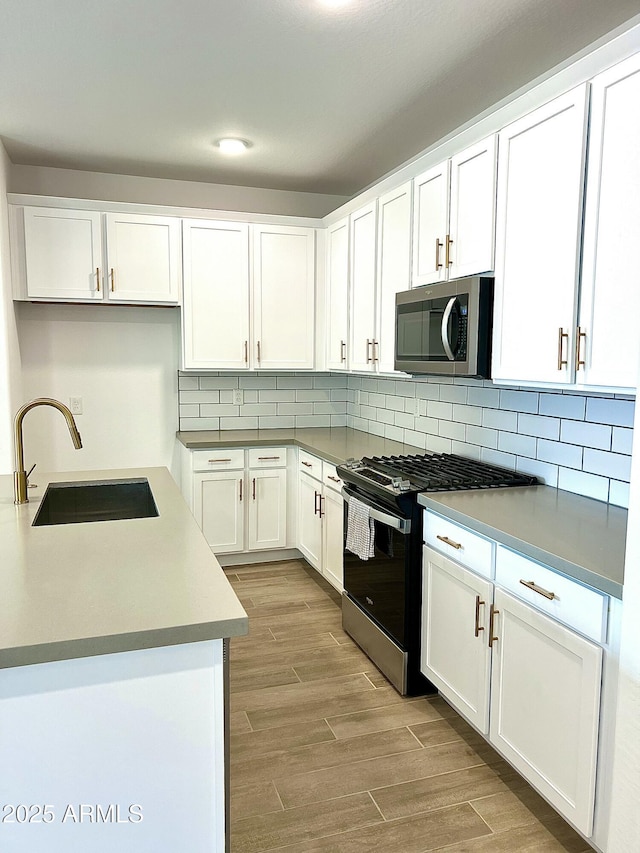 kitchen featuring sink, light hardwood / wood-style floors, white cabinets, and appliances with stainless steel finishes