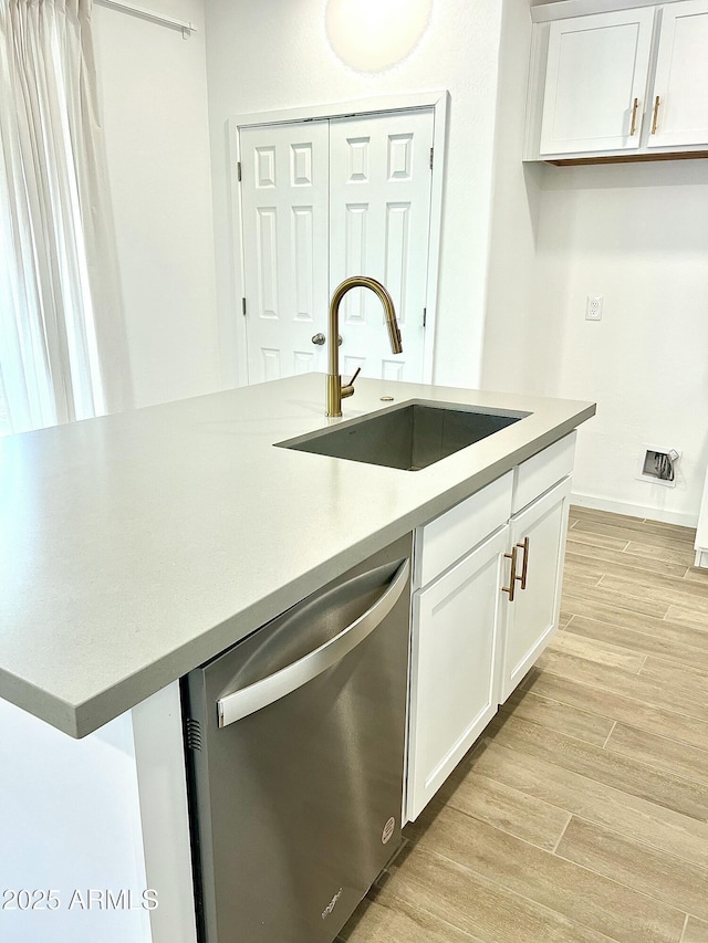 kitchen with white cabinetry, light hardwood / wood-style floors, dishwasher, and sink