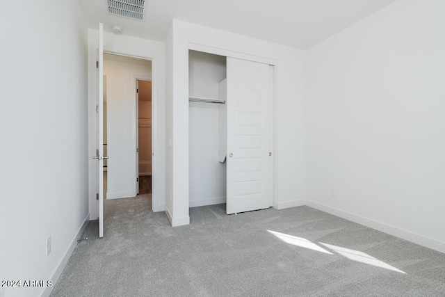 unfurnished bedroom with light carpet and a closet