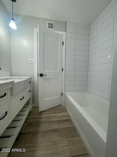 bathroom with shower / washtub combination, vanity, and hardwood / wood-style flooring