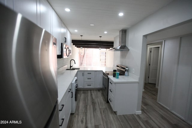 kitchen featuring pendant lighting, appliances with stainless steel finishes, dark wood-type flooring, wall chimney range hood, and white cabinetry