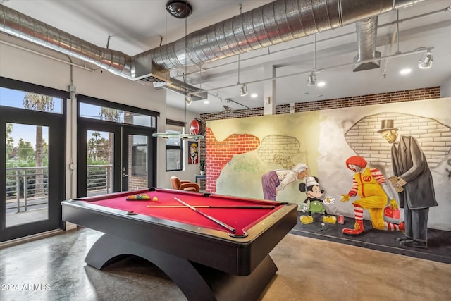 playroom featuring brick wall, concrete flooring, french doors, and billiards