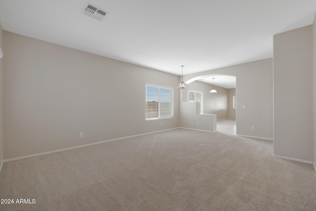 carpeted spare room featuring an inviting chandelier