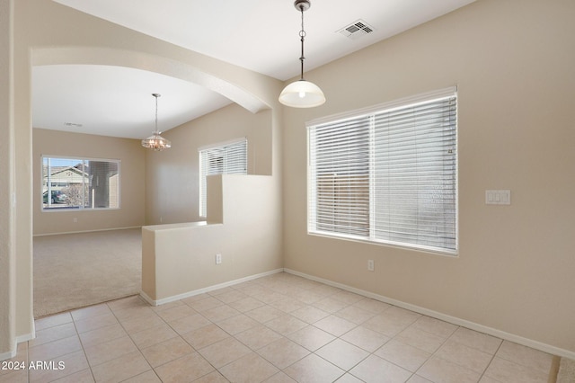 tiled spare room featuring an inviting chandelier