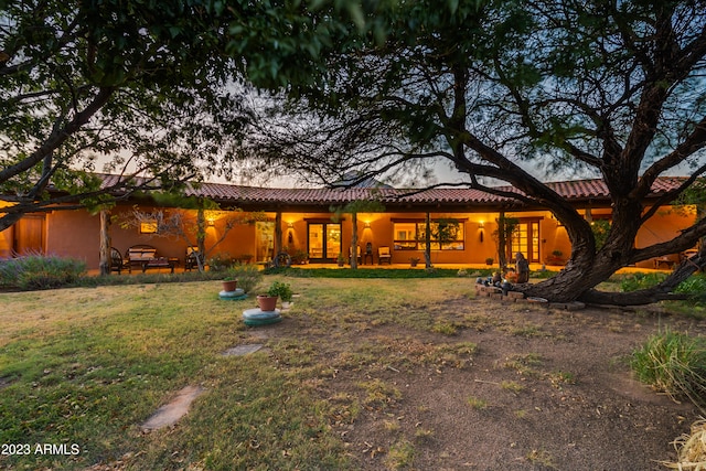 back house at dusk featuring a yard