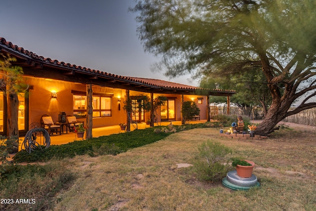 back house at dusk with a yard and a patio area