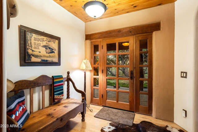 doorway to outside with light wood-type flooring and wooden ceiling