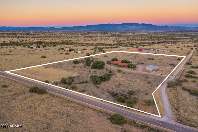 aerial view at dusk featuring a mountain view and a rural view