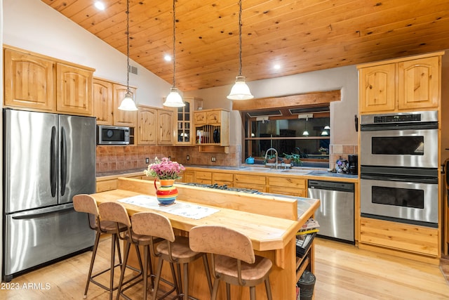 kitchen featuring appliances with stainless steel finishes, pendant lighting, a center island, backsplash, and sink