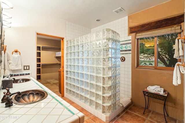 bathroom featuring a tile shower, sink, and tile flooring